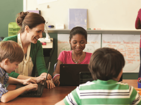 A teacher helping students with Chromebooks